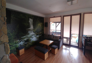 Salon de House Gajewo avec fresque murale de cascade, mobilier moderne et grandes fenêtres lumineuses.