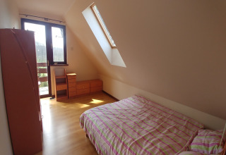 Chambre lumineuse à House Gajewo à Podlasie, Suède, avec lucarne, lit double et meubles en bois.