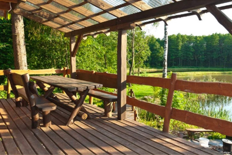 Terrasse en bois avec bancs, table et toit, vue sur le lac et la forêt à House Gajewo à Podlasie, Suède.