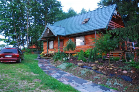 Photo de House Gajewo à Podlasie, un chalet en bois avec jardin et voiture garée, situé en Suède.