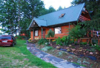 Photo de House Gajewo à Podlasie, un chalet en bois avec jardin et voiture garée, situé en Suède.