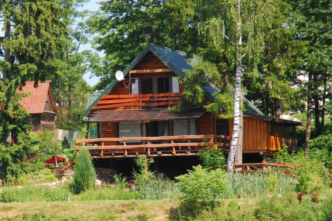 Chalet en bois nommé House Gajewo à Podlasie, en Suède, entouré d’arbres verts lors d’une journée d’été.