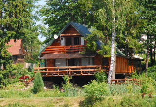 Chalet en bois nommé House Gajewo à Podlasie, en Suède, entouré d’arbres verts lors d’une journée d’été.