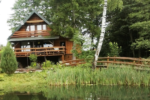 Chalet en bois nommé House Gajewo à Podlasie, en Suède, situé près d’un étang et entouré de verdure.