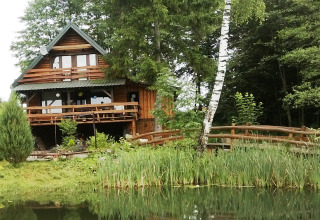 Chalet en bois nommé House Gajewo à Podlasie, en Suède, situé près d’un étang et entouré de verdure.