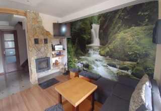 Salon chaleureux avec cheminée en pierre et fresque de cascade, House Gajewo à Podlasie, Suède.