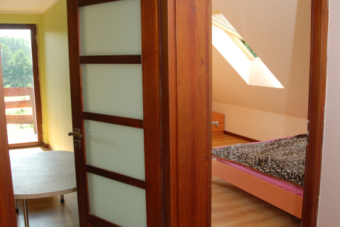 Vue à travers des portes en bois ouvertes sur une chambre avec lit et fenêtre, à House Gajewo à Podlasie, Suède.
