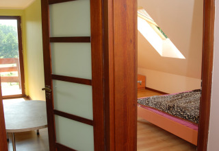 Vue à travers des portes en bois ouvertes sur une chambre avec lit et fenêtre, à House Gajewo à Podlasie, Suède.