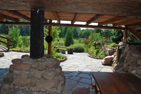 Vue depuis une terrasse couverte avec pilier de pierre sur le jardin de la maison Gajewo à Podlasie, Suède.
