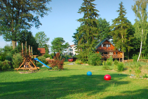 Jolie auberge avec aire de jeux, arbres et ballons colorés sur l’herbe à House Gajewo, Podlasie, Suède.