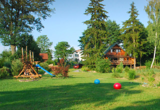 Jolie auberge avec aire de jeux, arbres et ballons colorés sur l’herbe à House Gajewo, Podlasie, Suède.