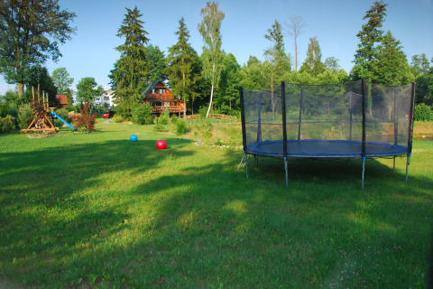 Grand jardin verdoyant avec trampoline et aire de jeux devant House Gajewo à Podlasie, en Suède.