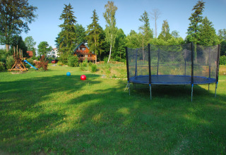 Grand jardin verdoyant avec trampoline et aire de jeux devant House Gajewo à Podlasie, en Suède.