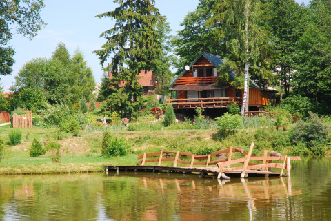 Chalet en bois au bord d’un étang avec passerelle, vu à House Gajewo in Podlasie, en Suède.