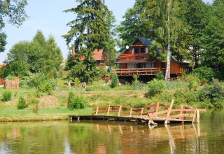 Chalet en bois au bord d’un étang avec passerelle, vu à House Gajewo in Podlasie, en Suède.