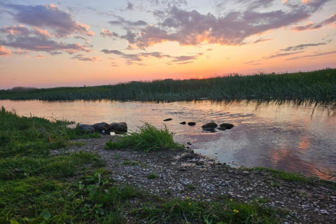 Coucher de soleil sur la rivière près de la maison Gajewo à Podlasie, Suède, avec rives verdoyantes.