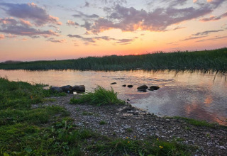 Coucher de soleil sur la rivière près de la maison Gajewo à Podlasie, Suède, avec rives verdoyantes.
