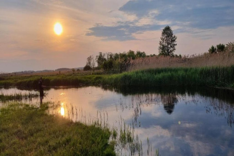 Coucher de soleil sur un lac paisible près de House Gajewo à Podlasie, Suède, avec une personne pêchant au bord.