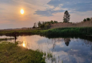 Coucher de soleil sur un lac paisible près de House Gajewo à Podlasie, Suède, avec une personne pêchant au bord.