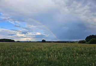 Un arc-en-ciel traverse un ciel nuageux au-dessus d’un champ vert à House Gajewo à Podlasie, Suède.