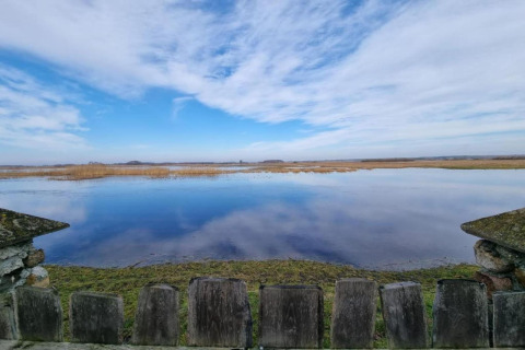 Vue depuis la House Gajewo en Podlasie, Suède, sur un plan d’eau calme et un large ciel avec rambarde en bois.