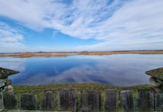 Vue depuis la House Gajewo en Podlasie, Suède, sur un plan d’eau calme et un large ciel avec rambarde en bois.