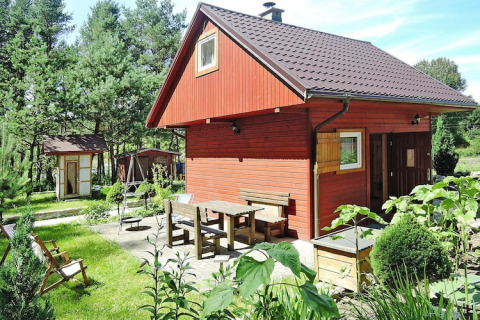 Outdoor photo of a red wooden lodge at Holiday resort in Wiselka with seating area for five persons.
