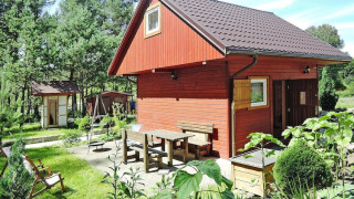 Buitenfoto van een rood houten vakantiehuis bij Holiday resort in Wiselka met plek voor vijf personen.