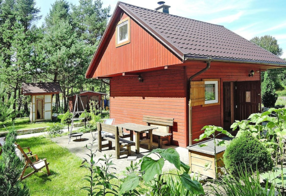 Outdoor photo of a red wooden lodge at Holiday resort in Wiselka with seating area for five persons.