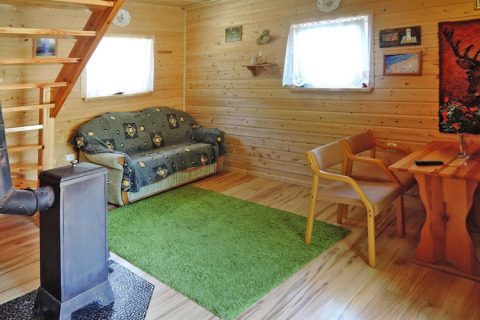 Cozy living room at Wiselka holiday lodge in Germany for 5 people, featuring wooden walls and stove.