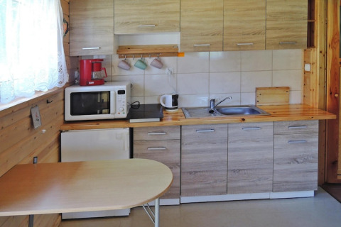 Compacte keuken met houten kasten, tafel en apparaten in het Wiselka vakantieverblijf in Duitsland.