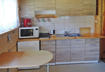 Compacte keuken met houten kasten, tafel en apparaten in het Wiselka vakantieverblijf in Duitsland.