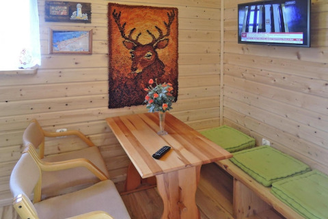 Hyggeligt opholdsrum i feriehus med træpaneler, hjortebillede, tv, bord og siddepladser i Wiselka.