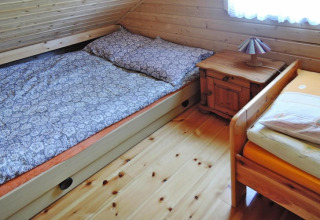 Bedroom in holiday resort in Wiselka, Germany, featuring two beds, wooden furniture, and sloped ceiling.