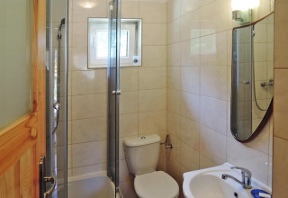 Small bathroom with shower, toilet, sink and mirror in a holiday lodge for 5 people in Wiselka, Germany.