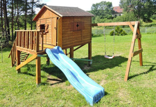 Legeplads med trælejehus, blå rutsjebane og gynge i ferieanlægget Wiselka, Tyskland, til 5 personer.