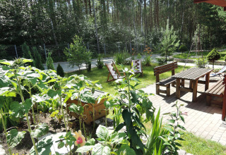 Hyggelig have med træmøbler ved Holiday resort i Wiselka, Tyskland, omgivet af grønne planter og skov.
