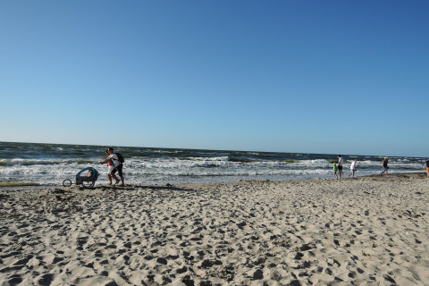 Mensen genieten van het strand en de zee bij Ustecka Osada 45m2 in Denemarken op een zonnige dag.