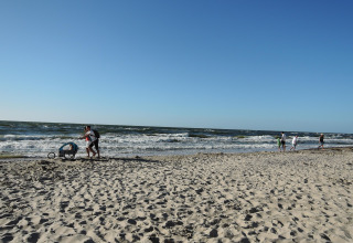 Mensen genieten van het strand en de zee bij Ustecka Osada 45m2 in Denemarken op een zonnige dag.