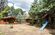Deux chalets en bois et une aire de jeux avec toboggan et balançoires entourés d’arbres en Allemagne.