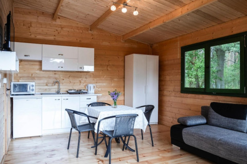 Gemütliches Ferienhaus mit Holzwänden, moderner Küche, Esstisch, Sofa und Ausblick auf Wald in Deutschland.