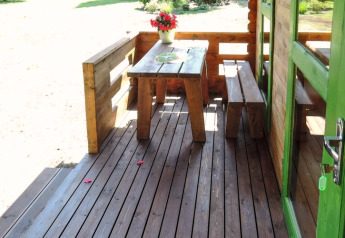 Véranda en bois avec table, bancs et fleurs à Holiday homes, Kodrabek-35 m², Allemagne.