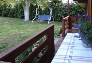 View from a wooden porch with flowers, bench, and garden swing at Bungalows Lubin Type A Jolanta, Germany.