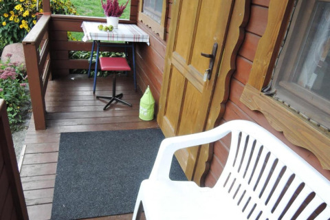 Accogliente veranda in legno presso Bungalows Lubin Type A Jolanta con panca, tavolo e fiori in Germania.