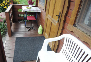 Accogliente veranda in legno presso Bungalows Lubin Type A Jolanta con panca, tavolo e fiori in Germania.