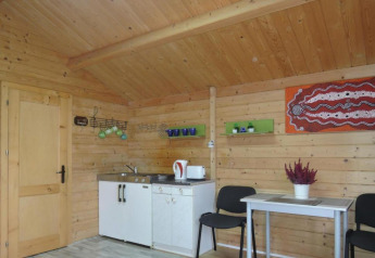 Vista interna di una baita in legno con angolo cottura, tavolo da pranzo, sedie e decorazione murale.