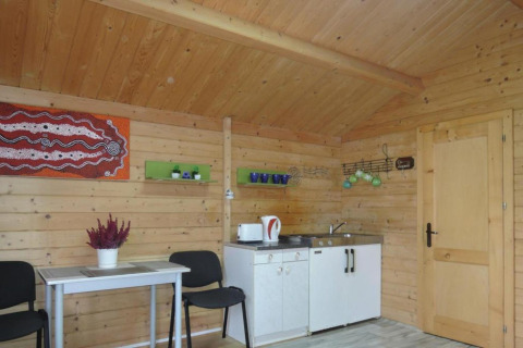 Interior view of Bungalows Lubin Type A Jolanta in Germany, featuring wood paneling, kitchenette, and table.
