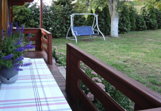 Veranda in legno con fiori, tavolo e vista sul giardino con altalena a Bungalows Lubin Type A Jolanta.