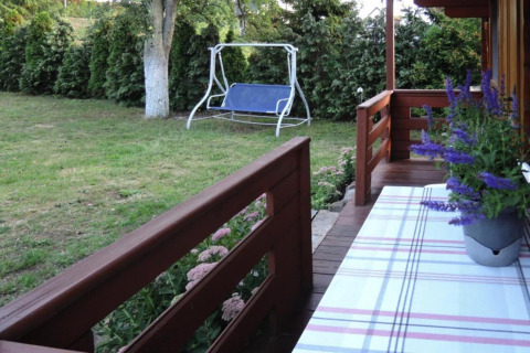 Vue du porche d’un chalet en bois avec jardin, balançoire et pot de fleurs en Allemagne.