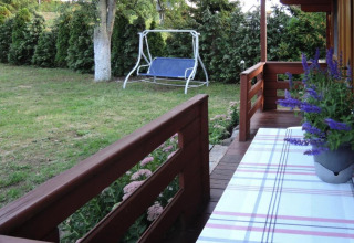 View from the porch of a wooden cabin with garden swing and flower pot, Lubin, Germany.